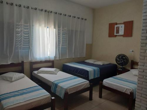 a room with three beds and a window at Hotel JF2 in Pirassununga