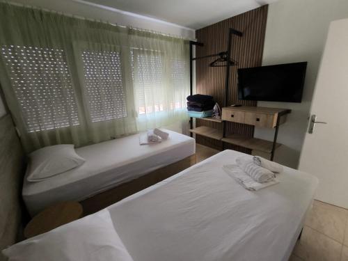 two beds in a room with a tv and a bed sidx sidx sidx at Fotis Resort in Iraklitsa