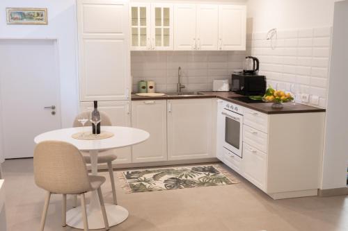 a kitchen with white cabinets and a table and a table and chairs at Pupi Studio Apartment Trogir in Trogir
