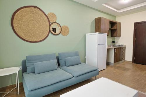 a living room with a blue couch and a white refrigerator at 46 Serviced Apartments in Amman