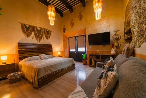 a bedroom with a bed and a tv and a couch at Hotel Boutique Casa Lanz XVII in Campeche