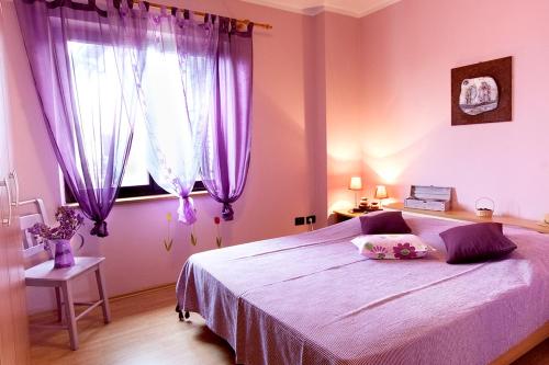a bedroom with a bed with purple curtains and a window at Apartman Orbanići in Orbanići