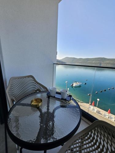 a table with two cups on a balcony with a view of the ocean at Apartmani Leženić M in Neum