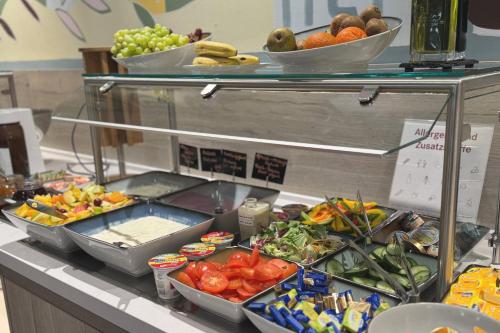 a buffet with bowls of fruits and vegetables on a counter at Holiday Inn - the niu, Yen Hamburg City by IHG in Hamburg