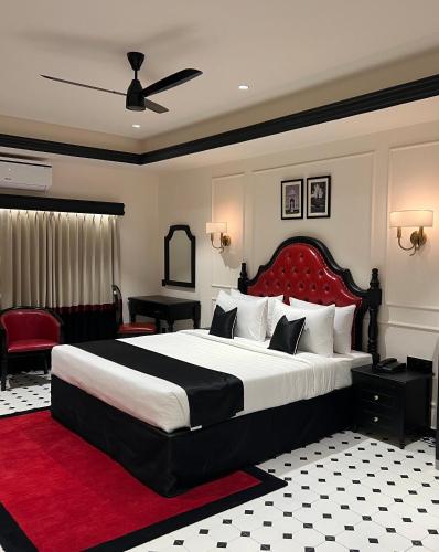a bedroom with a large bed with a red headboard at Hotel Bengal Kutir in Rāiganj