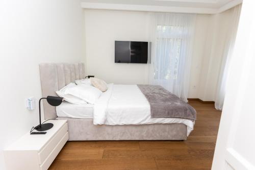 a white bedroom with a bed and a television at Villa Regens 1928 in Meljine