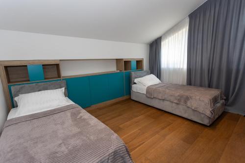two beds in a room with blue walls and wooden floors at Villa Regens 1928 in Meljine