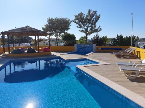 a swimming pool with chairs and a gazebo at Casinha da Galé in Galé