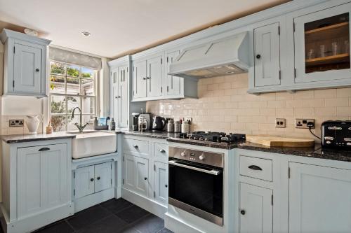 Una cocina con gabinetes blancos y un horno de estufa. en Central Lymington Retreat, en Lymington