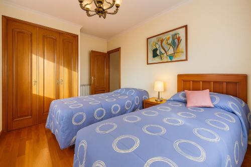 a bedroom with two blue beds and a chandelier at Chalet en Sanxenxo con hermosas vistas y gran privacidad in Sear