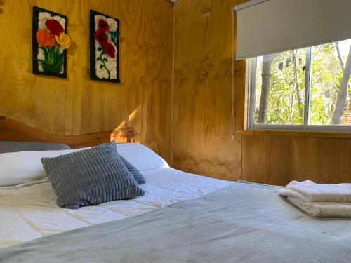 a bedroom with a white bed with a window at CABAÑA Remanso2 in Futaleufú