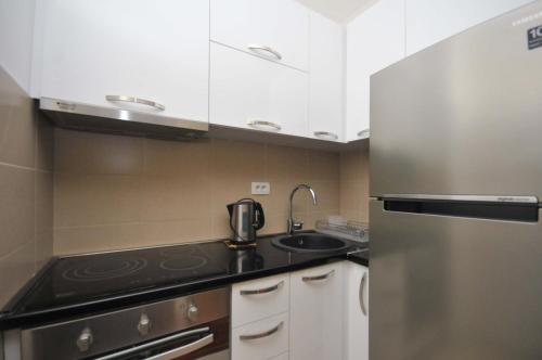 a kitchen with a sink and a stainless steel refrigerator at Seaside Apartments Petrovac in Petrovac na Moru