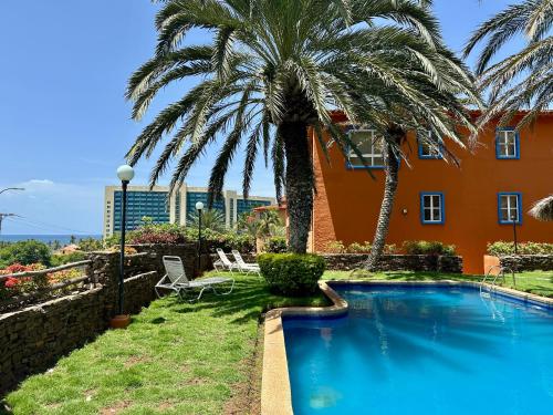 a swimming pool with palm trees and a building at Apto para 3 A pasos del Downtown y Playa Veleros in Pampatar