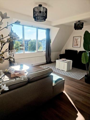 a living room with a couch and a large window at Sonsbeek city apartment "De Merel" in Arnhem