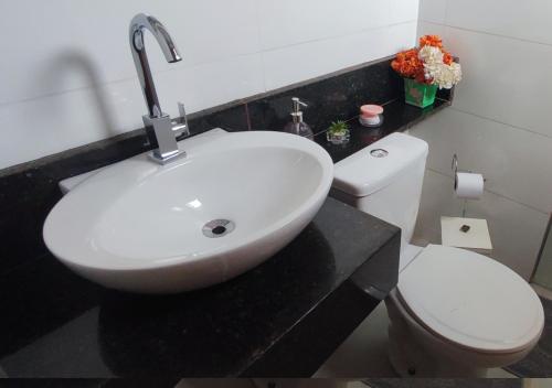 a bathroom with a white sink and a toilet at Pousada La Belle de Jour in Chapada dos Guimarães