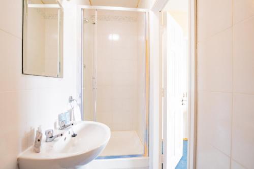 une salle de bain blanche avec lavabo et douche dans l'établissement Spacious & Affordable 3 Bed Apt, à Galway
