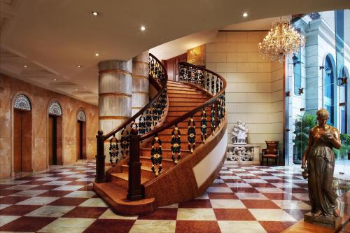 a spiral staircase in a lobby with a statue at Hotel The Royal Plaza in New Delhi