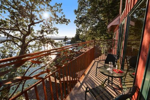 a table and chairs on a balcony with a view of the water at Salishan Tree House Suite in Cowichan Bay