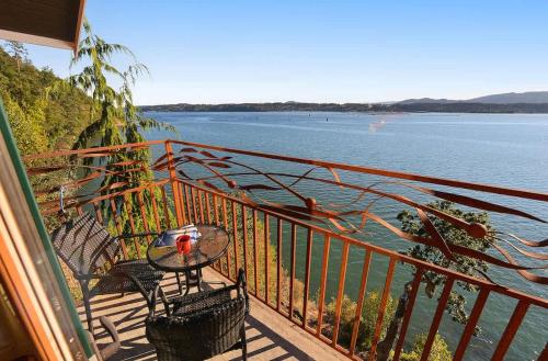a balcony with a table and chairs next to the water at Salishan Tree House Suite in Cowichan Bay