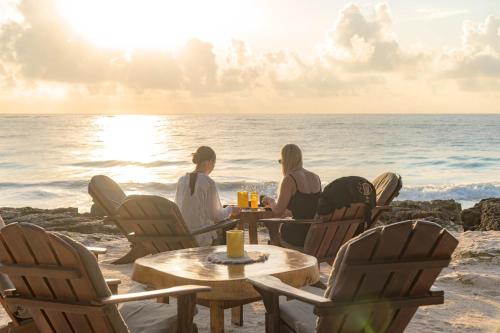 a group of people sitting at a table on the beach at Diamante K - Inside Tulum National Park in Tulum