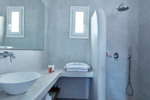 a white bathroom with a sink and a shower at Mykonos Waves Beach House & Suites in Ornos