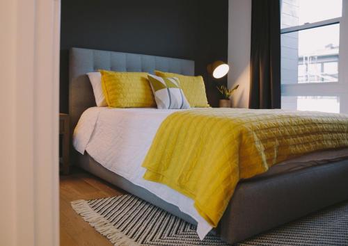 a bedroom with a bed with a yellow blanket at Morden 2BR Apt with city views in Manchester