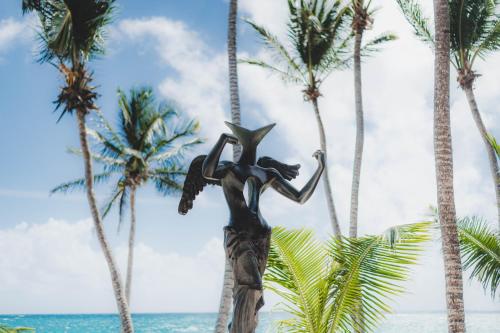 a statue of a woman standing in front of palm trees at Diamante K - Inside Tulum National Park in Tulum