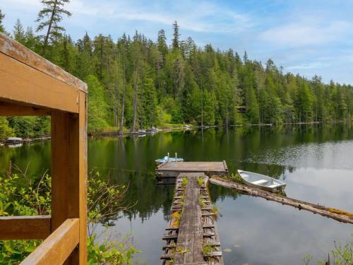 un quai avec un bateau sur un lac dans l'établissement The Lakeside Cottage, à Gibsons