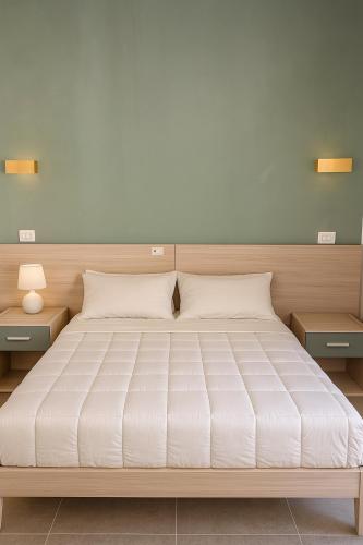 a bedroom with a large bed with two night stands at Le dune relax con cucina & piscina in San Teodoro