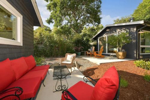 a patio with a red couch and chairs at The Bayside Cottage in North Saanich