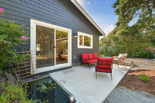 a patio with two red chairs and a table at The Bayside Cottage in North Saanich