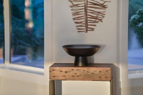 a bowl on a wooden stand in front of a window at Island Luxury Oceanside Estate in Saanichton