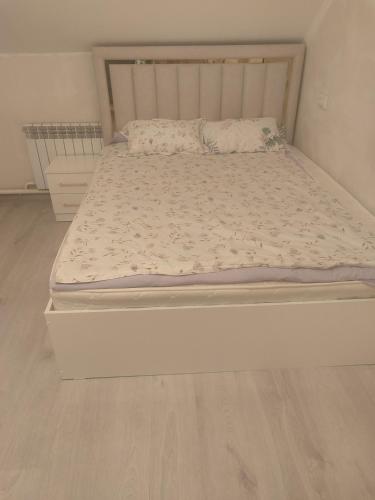 a bed in a bedroom with a wooden floor at Guest House NAZIRA in Kazarman