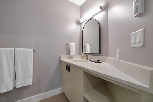 a white bathroom with a sink and a mirror at Island Luxury Oceanside Estate in Saanichton