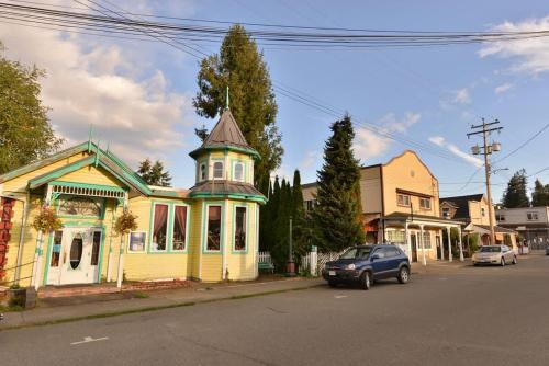 a blue car parked in front of a yellow house at Gulf Island View Suite in Chemainus