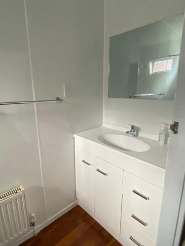 a white bathroom with a sink and a mirror at The Ohakune Central Cabins in Ohakune