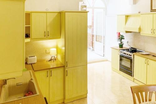 a kitchen with yellow cabinets and a stove top oven at Bougainvillea Breeze & Marina View - Happy Rentals in Cospicua