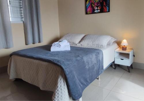 a bedroom with a bed with a blue blanket on it at Pousada La Belle de Jour in Chapada dos Guimarães