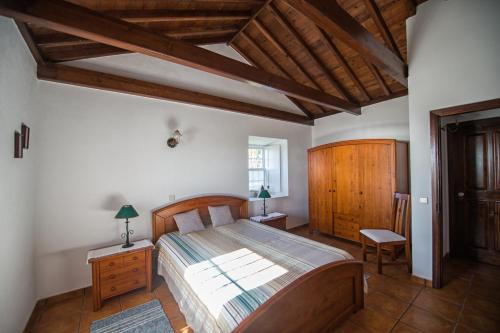 um quarto com uma cama grande e mobiliário em madeira em Casas do Capelo em Varadouro