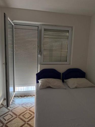 a bedroom with a bed and two windows with blinds at Tatjana apartman blue in Sutomore