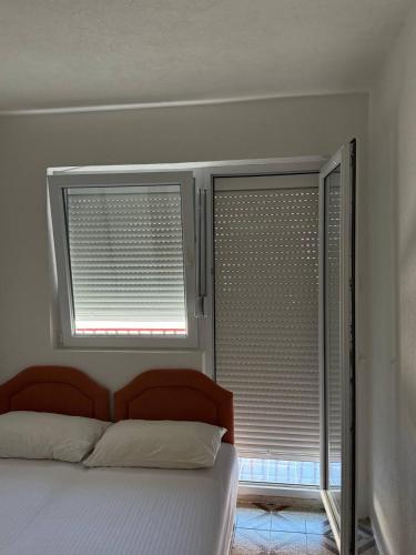 a bedroom with a bed and two windows with blinds at Tatjana apartman blue in Sutomore
