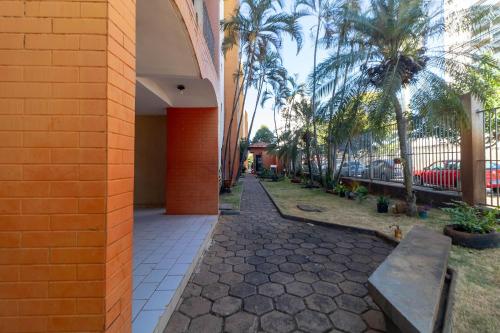 a sidewalk with a bench next to a building with palm trees at Ed. Residencial Negrão Lima | Goiânia in Goiânia