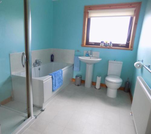 a bathroom with a tub and a toilet and a sink at Bosta 12 Knock in Stornoway