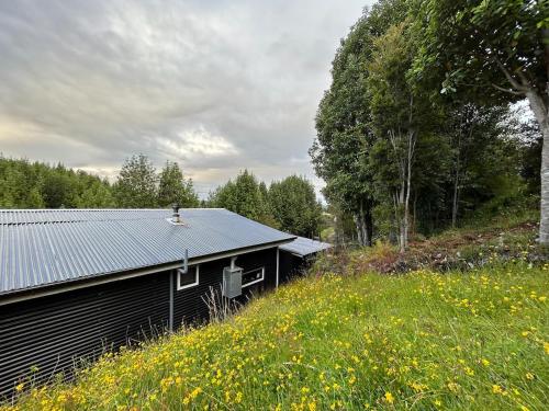 a black building sitting in a field of flowers at Blue Cabin - La Herradura 