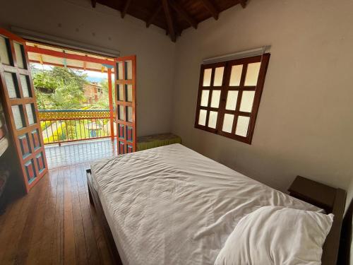 a bedroom with a white bed and a window at Hostería El Paraíso in Jardin