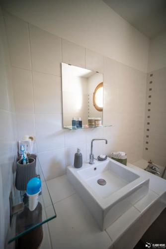 une salle de bain blanche avec un lavabo et un miroir dans l'établissement La Villa Coucou, à Nîmes
