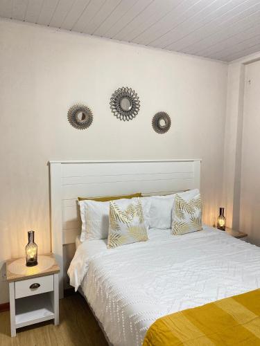 a bedroom with a white bed with two mirrors on the wall at Wanansha Apartments in Gaborone