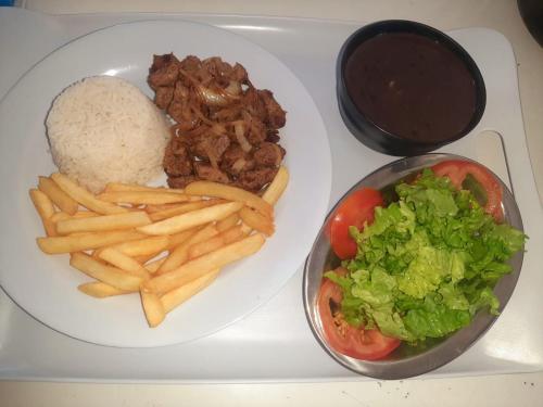 une assiette de nourriture avec des frites et du riz dans l'établissement Apartamento Brisa 201, à Pedra de Guaratiba