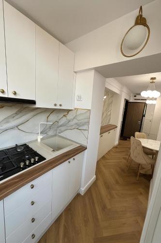 a kitchen with white cabinets and a sink and a table at Luxury Stay in Brăila