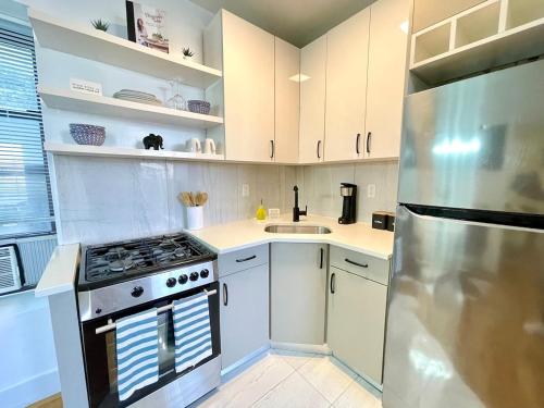 a kitchen with a stove and a stainless steel refrigerator at Madison Ave Oasis in New York